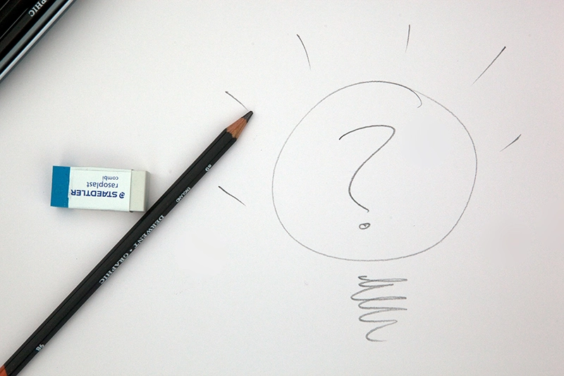 Image d'une feuille avec un dessin d'ampoule et d'un point d'interrogation, dessiné au crayon à papier
