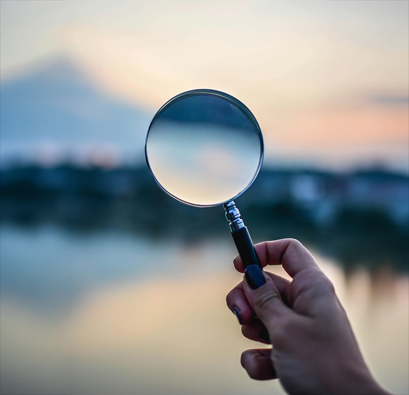 Image d'une main tenant une loupe