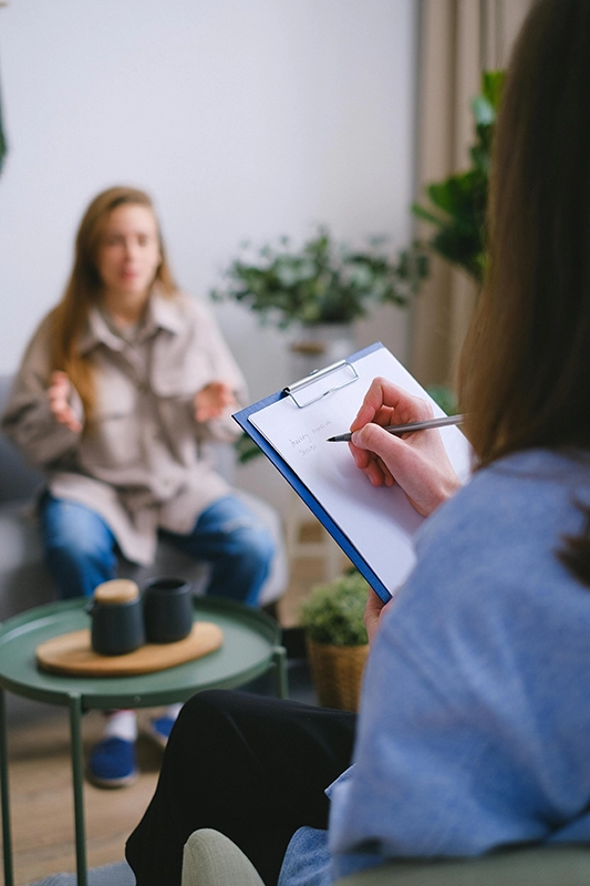 Photo d'une coach prenant des notes face à une femme qui parle